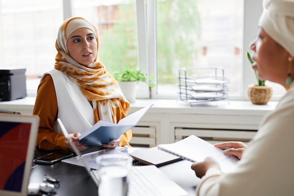 Two women in a professional office setting discussing documents during a meeting.